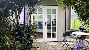 A patio area with a gravel floor, a table with chairs, and a covered seating area with a view of the outdoors. - Casa Azure - quaint studio with a mediterranean touch (Kangaroo Valley)
