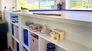 A kitchen with white cabinets, a wooden countertop, and a view of greenery outside. - Casa Azure - quaint studio with a mediterranean touch (Kangaroo Valley)