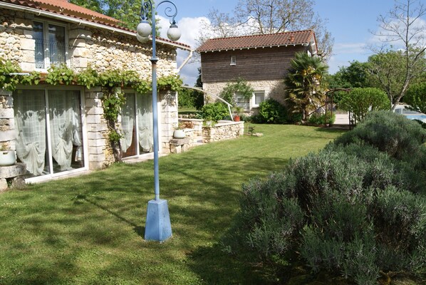 A stone house with a tiled roof, a well-maintained lawn, and a metal street lamp.