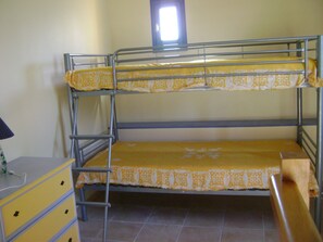 A bunk bed with yellow bedding and a small window above the top bunk.
