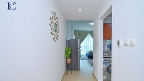 A hallway with a refrigerator, a potted plant, and a washing machine in the background. - Lake View Brand New Studio in X1 Tower JLT - LND (Dubai)