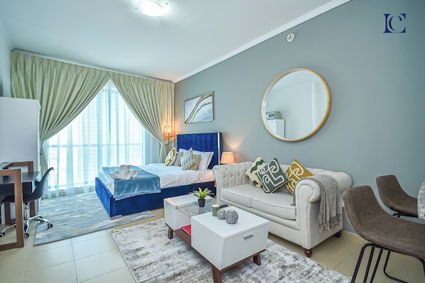 A modern hotel room with a bed, a sofa, a desk, and a dining area.