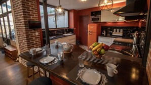 A modern kitchen with a brick wall, wooden countertop, and stainless steel appliances.