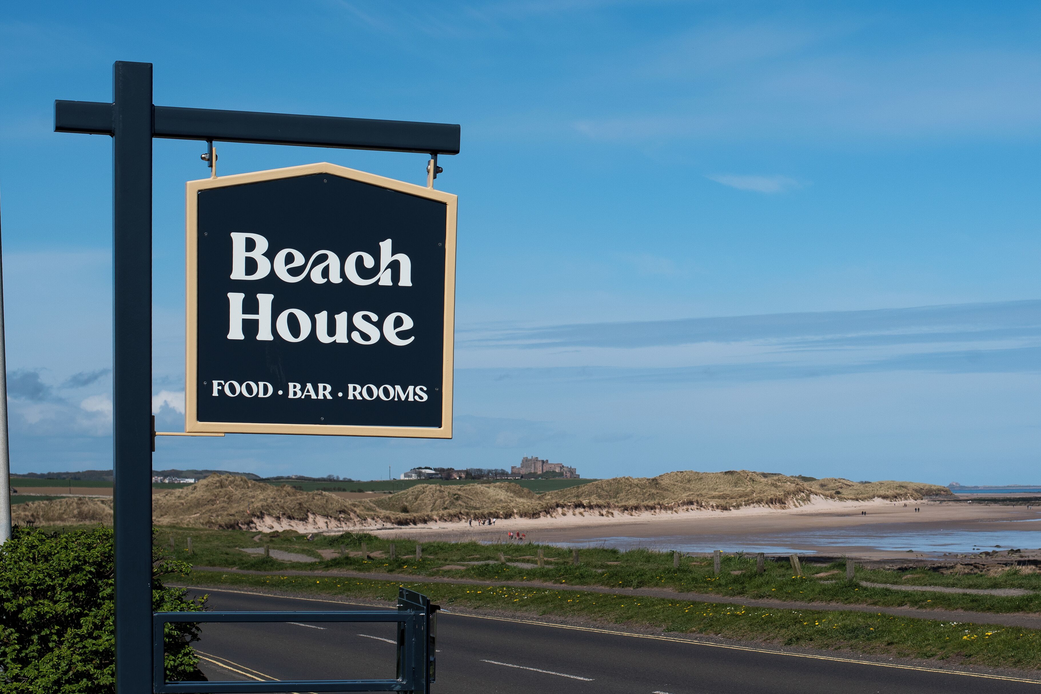 Une enseigne indiquant « Beach House », avec les commodités suivantes : RESTAURATION, BAR, CHAMBRES.