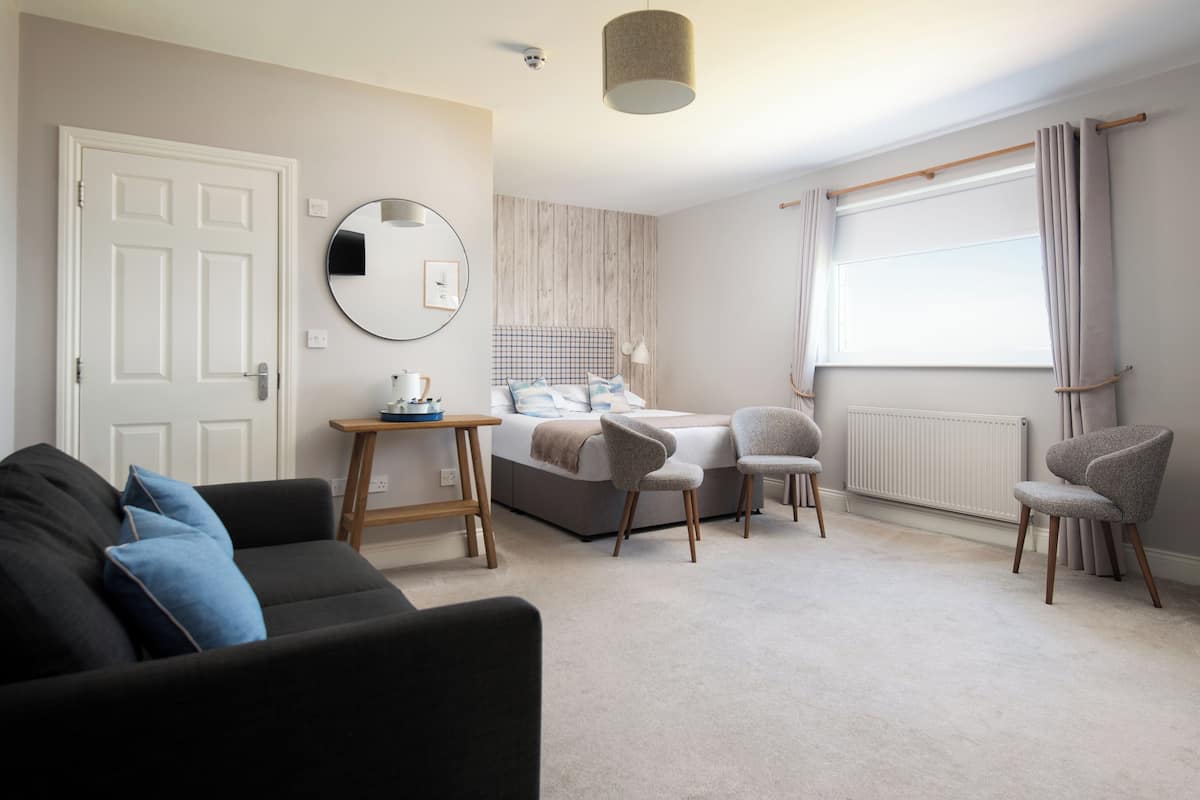 A bedroom with a bed, bedside table, and a window with curtains.