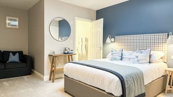 Un dormitorio con una cama, un escritorio, una silla, un sofá, un espejo y una puerta.