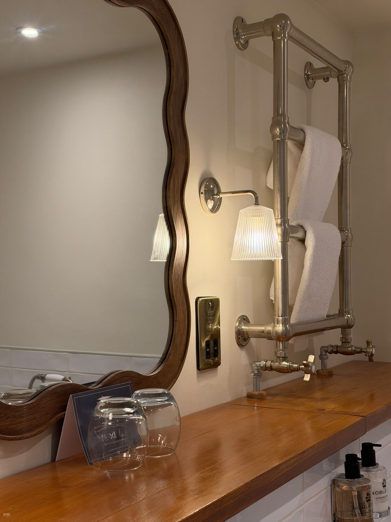 Un baño con tocador de madera, un perchero, un espejo y un aplique de pared.