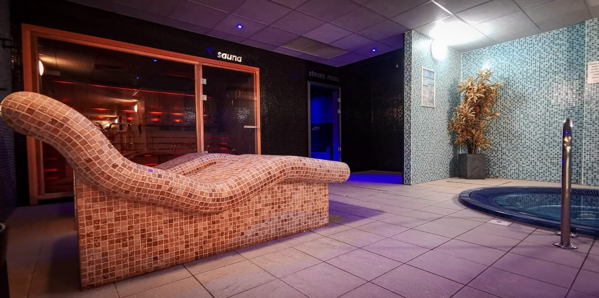 A spa area with a mosaic-tiled massage chair, a steam room, and a small indoor pool.