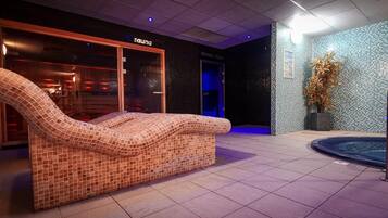 Een wellnessruimte met een massagestoel met mozaïektegels, een stoomruimte en een klein binnenzwembad.