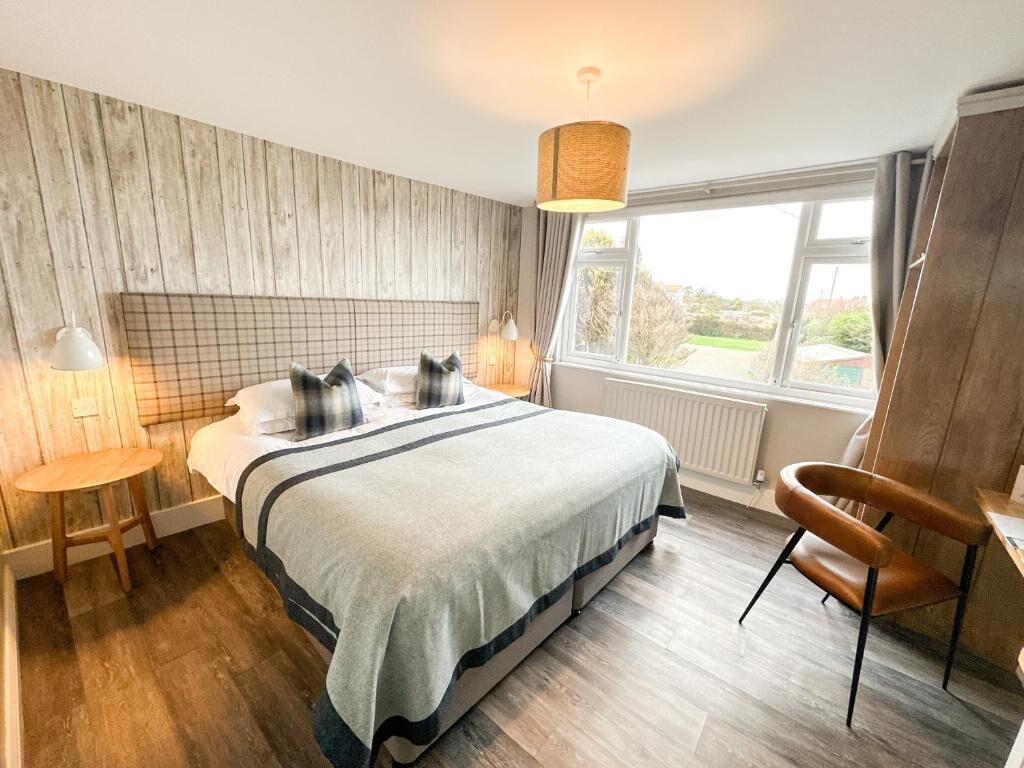 A bedroom with a bed, bedside tables, a chair, a window, and a view of the outdoors.