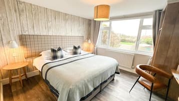 A bedroom with a bed, bedside tables, a chair, a window, and a view of the outdoors.