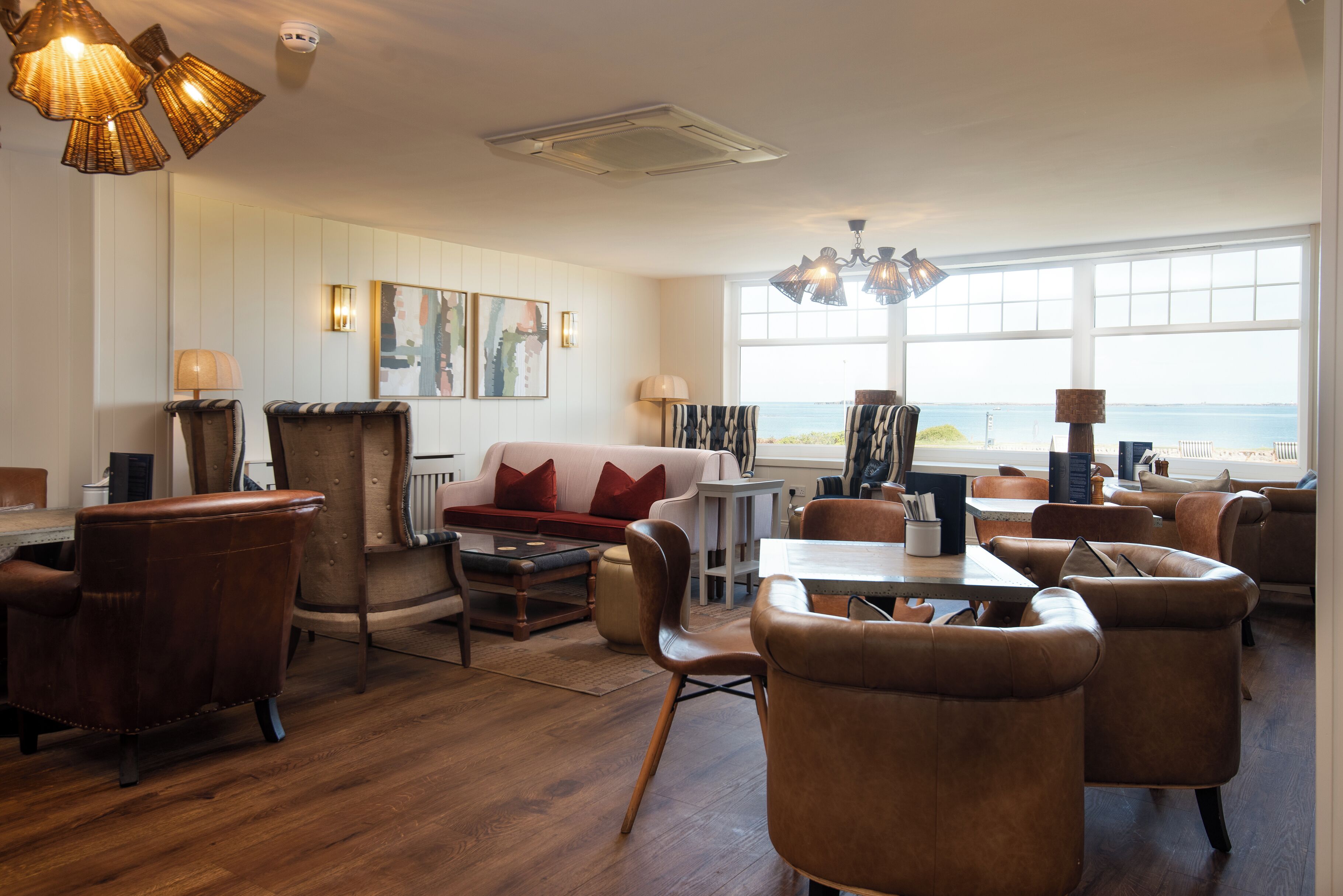 A spacious living area with leather furniture, a large window with a view, and modern lighting fixtures.