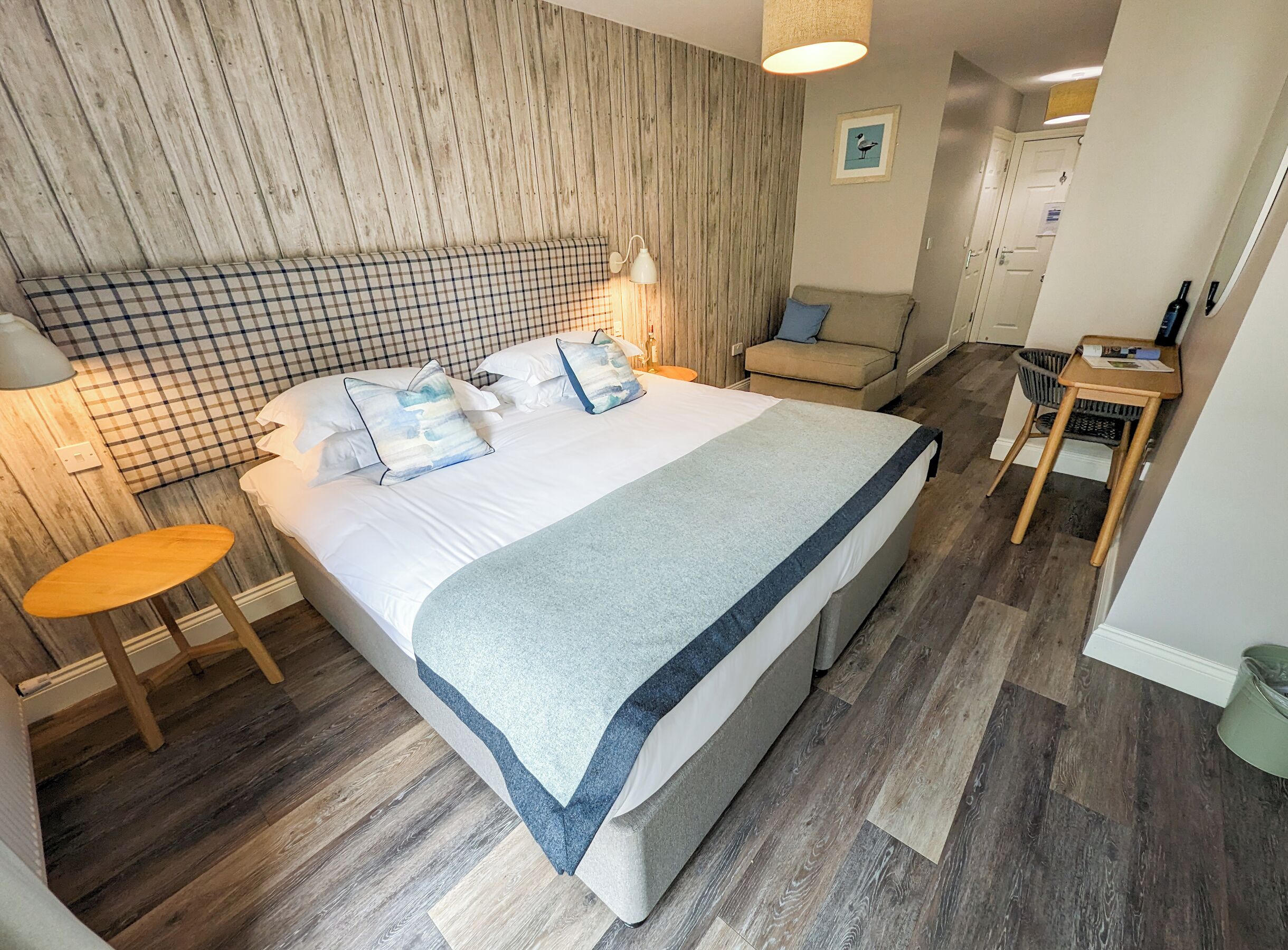 Ein ordentlich eingerichtetes Schlafzimmer mit einem Bett, Nachttischen, einem Sessel und einem kleinen Tisch.