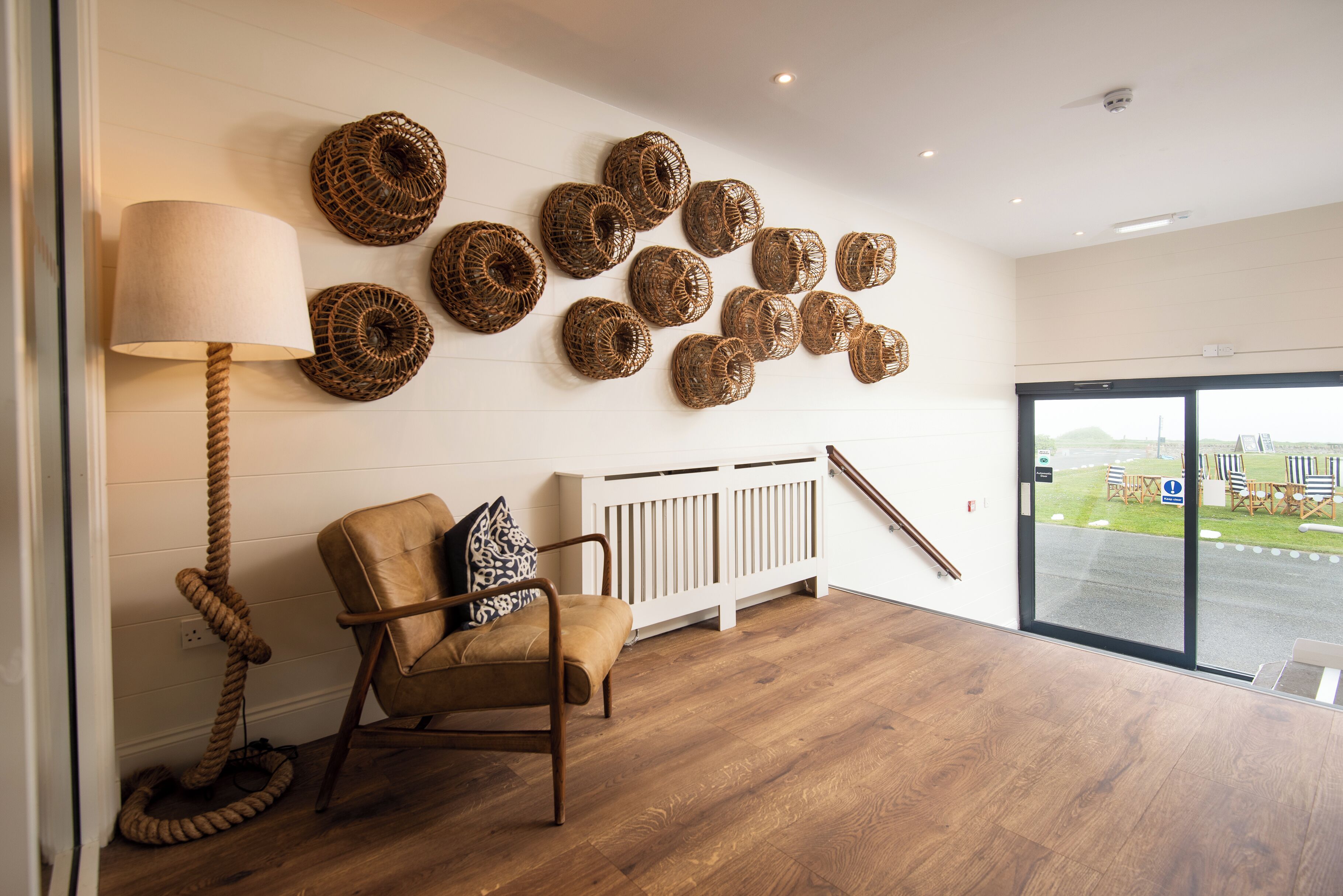 A room with a wooden floor, a brown leather chair, a white radiator, and a large window with a view of the outdoors.