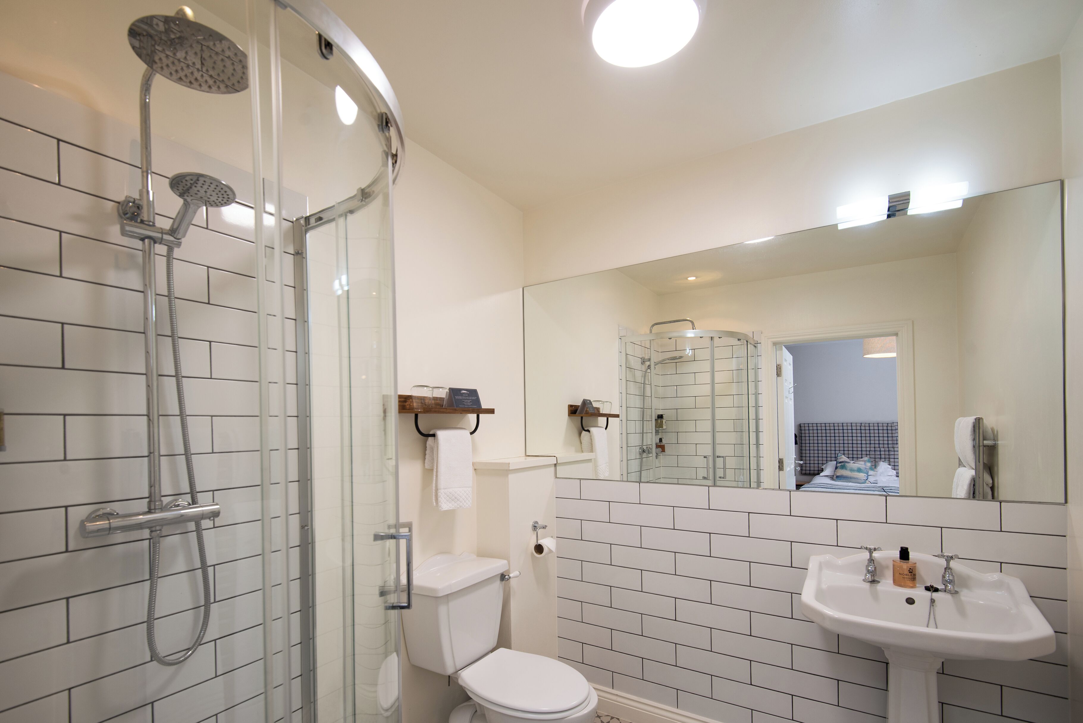 A modern bathroom with a glass shower enclosure, a white toilet, and a sink with a mirror above.