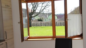 A room with a large window, a table with a bowl, and a chair. - Light-filled, spacious apartment, direct access to terrace and lawn (Ühlingen-Birkendorf)