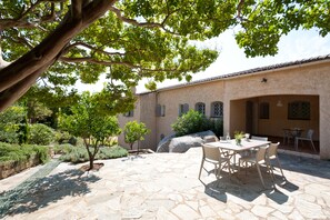 A patio with stone flooring, outdoor furniture, and a view of a building with arches and a tiled roof.