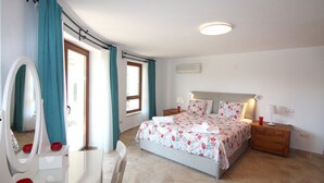 A bedroom with a bed, a bedside table with a lamp, a mirror, and a window with curtains. - Romantic Stone Villa With Private Pool Just 100m From The Beach (Kas)