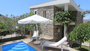 A modern outdoor pool area with lounge chairs and a white umbrella. - Romantic Stone Villa With Private Pool Just 100m From The Beach (Kas)