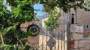 A stone wall with a metal gate, a sign with 'FISTIK 3 EV' written on it, and a building with a stone facade in the background. - Romantic Stone Villa With Private Pool Just 100m From The Beach (Kas)