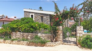 A stone house with a garden, a metal gate, and a clear blue sky. - Romantic Stone Villa With Private Pool Just 100m From The Beach (Kas)