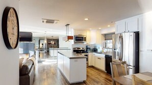 Una cocina moderna con armarios blancos, electrodomésticos de acero inoxidable y una isla central.