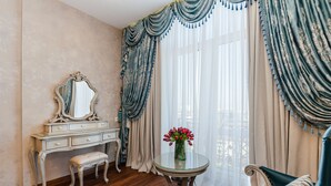 A room with a vanity, a mirror, a bench, a round table with a vase of flowers, and a sofa. - GREGORY Boutique Hotel Chisinau (Chisinau)