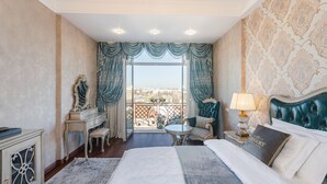 A spacious bedroom with a large bed, a sitting area with a chair and table, a dresser, and a view of the city through a balcony. - GREGORY Boutique Hotel Chisinau (Chisinau)