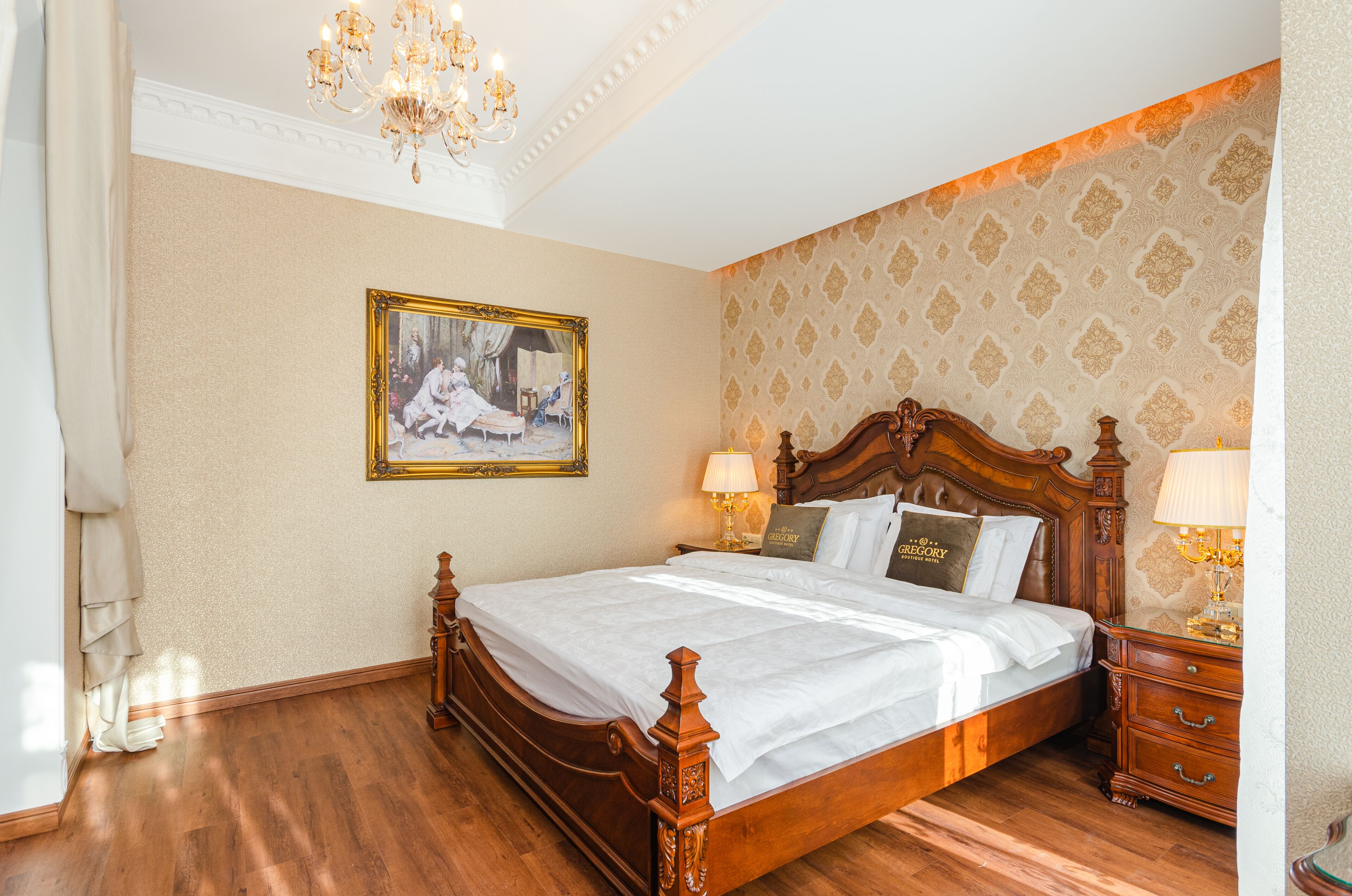 A bedroom with a wooden four-poster bed, a chandelier, a framed picture on the wall, and a patterned wallpaper.