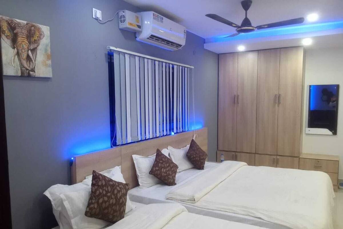 A hotel room with two beds, a ceiling fan, an air conditioning unit, and a wardrobe.
