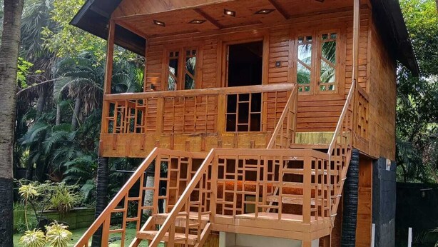 A wooden house with a balcony, a staircase, and a small garden area. -  Leisure Inn Resort by NHospitality (Cheyyur)