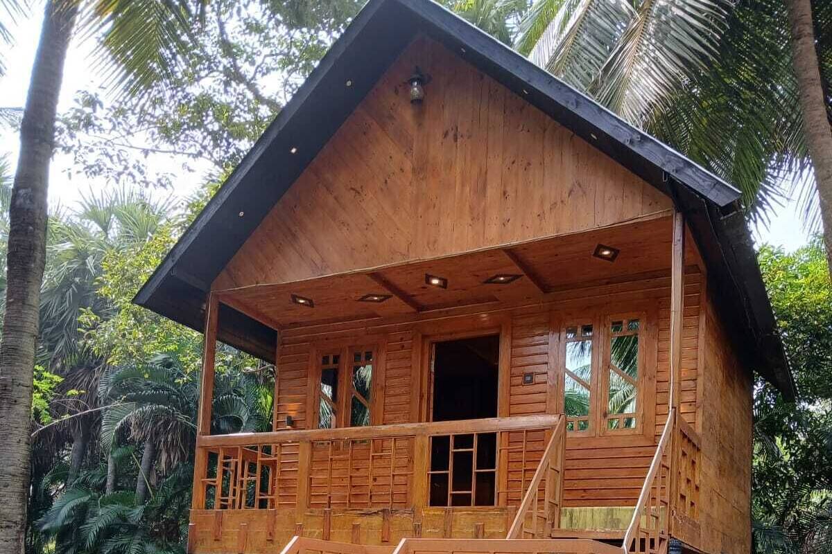 A wooden house with a balcony, a staircase, and a small garden area.