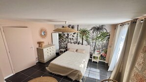 Une chambre à coucher comprenant un lit, une commode, une table de chevet et une fresque murale.