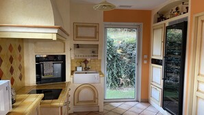 A kitchen with a built-in oven, a sink, and a window leading to a garden.