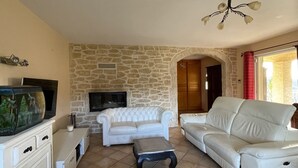 A living room with stone walls, a white sofa, a television, and a fireplace.