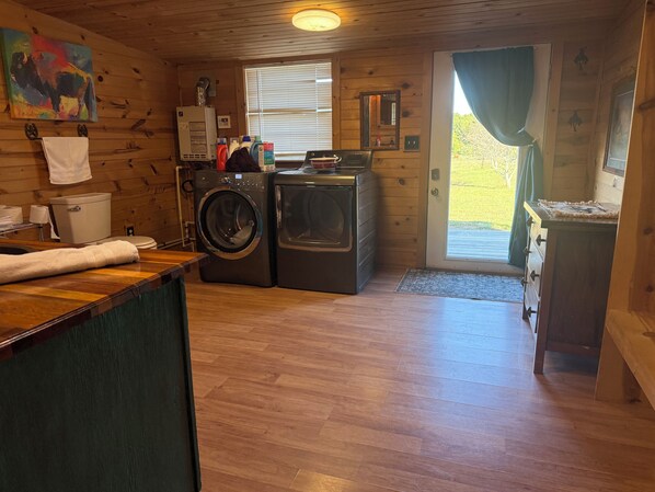 A compact laundry room with a washing machine and dryer, a small sink, and a window with blinds. - Rustic bunkhouse on authentic working ranch in the beautiful Tennessee mountains (Altamont)