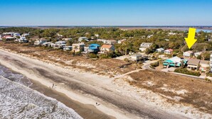 Vista aérea de una zona residencial costera con casas, una playa y cielo despejado.