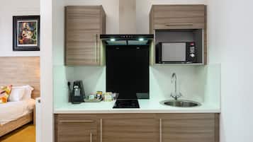 Una cocina compacta con microondas, cafetera y fregadero.