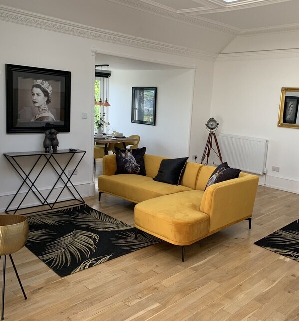 A living room with a yellow sofa, a black and white patterned rug, and a framed picture on the wall. - The Clarendon (Dundee)