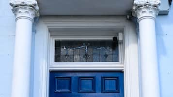 Een blauwe deur met een geel bord, omlijst door witte zuilen, en een bord erboven met de tekst 'The Clarendon'.