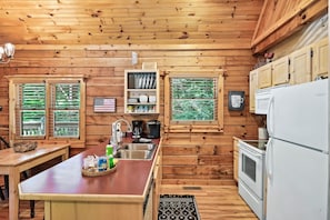 Cozy cabin-style kitchen with a central island, sink, coffee maker, and refrigerator.
