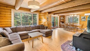 A log cabin interior with a sectional sofa, dining table, chairs, and a fireplace. - Custom Log Cabin with Great Amenities! (Leavenworth)