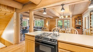 A wooden cabin interior with a kitchen, dining area, and a fireplace. - Custom Log Cabin with Great Amenities! (Leavenworth)