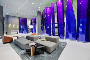 Un vestíbulo moderno con mostrador de recepción, zona de estar y paneles decorativos azules.