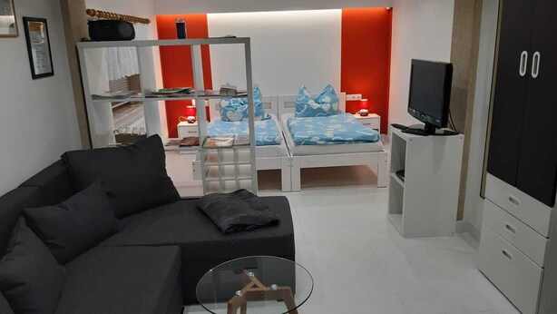 Une chambre à coucher moderne avec un lit, un canapé, une télévision et une armoire.