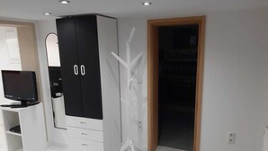 Une chambre moderne avec une grande armoire, un téléviseur posé sur un meuble et une porte donnant sur une autre pièce.