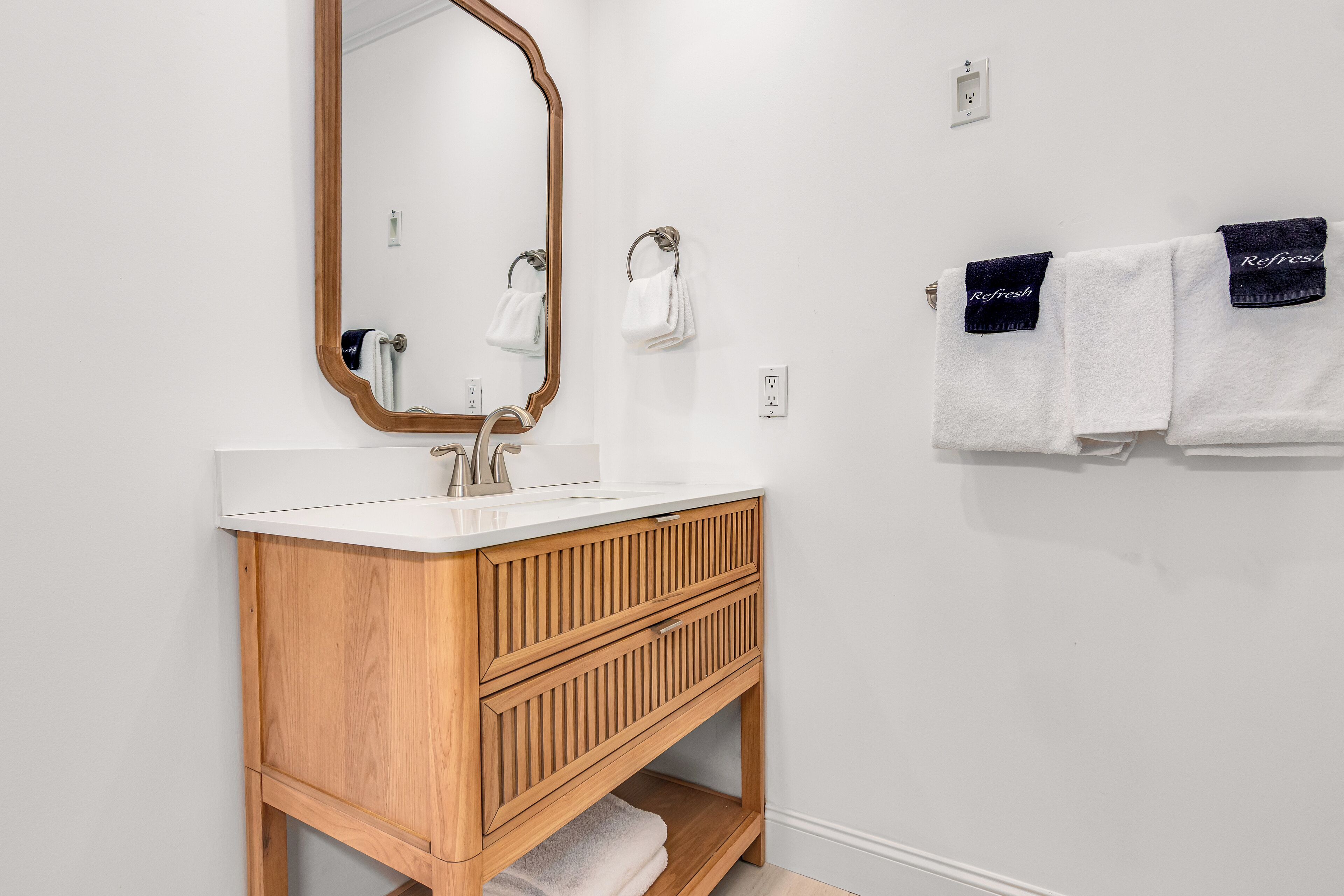 Un baño con tocador de madera, un espejo y dos toallas colgadas en la pared.