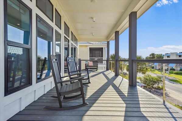 A covered porch with rocking chairs and a view of the street.