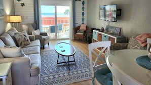 A living room with a sofa, a small table, a television, and a view of the outdoors. - 202 - Adorable 1 bedroom unit - sleeps 6 (New Smyrna Beach)