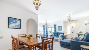 Un vaste espace de vie comprenant un coin repas avec une table, un canapé bleu et une cuisine visible au fond.